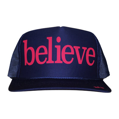 Believe in pink ink on the front panel of a classic mesh navy trucker cap with an adjustable snapback