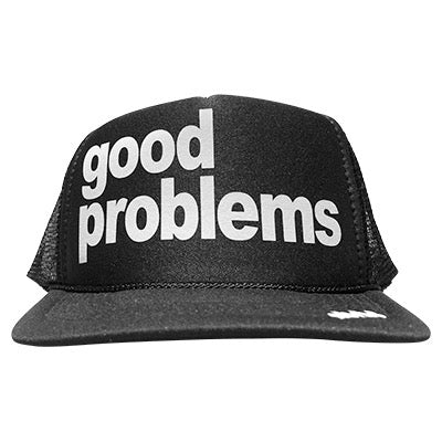 Good problems in white ink on the front panel of a black mesh trucker cap with an adjustable snapback