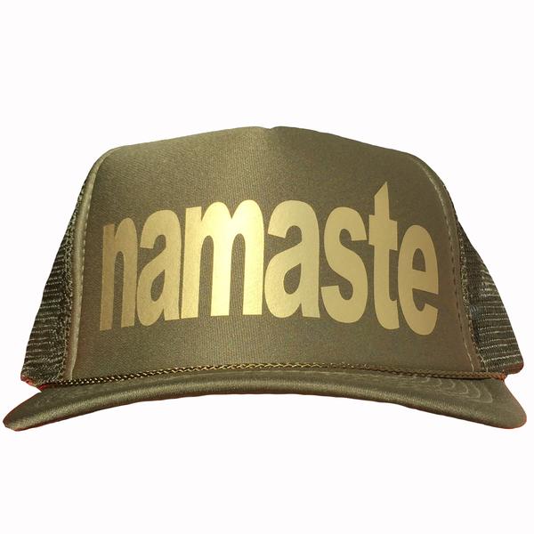 Namaste in gold ink on the front panel of a classic mesh olive trucker cap with an adjustable snapback