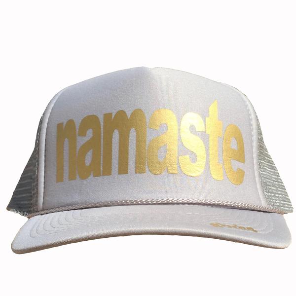 Namaste in gold ink on the front panel of a classic mesh gray trucker cap with an adjustable snapback