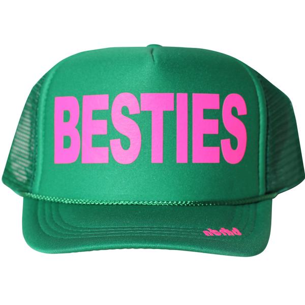 Kid's Besties in neon pink ink on the front panel of a classic mesh green trucker cap with an adjustable snapback