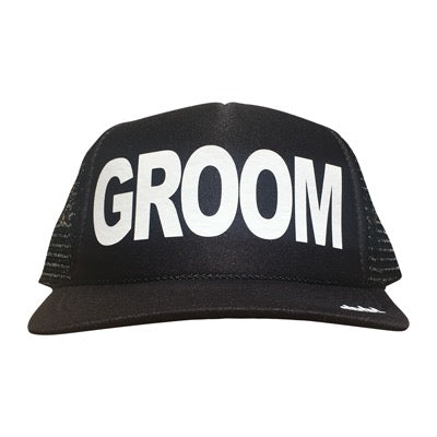 Groom in white ink on the front panel of a black mesh trucker cap with an adjustable snapback